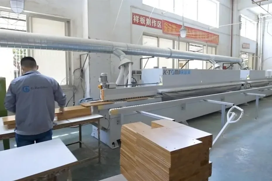 Operator beside panel-processing equipment in a cabinet workshop