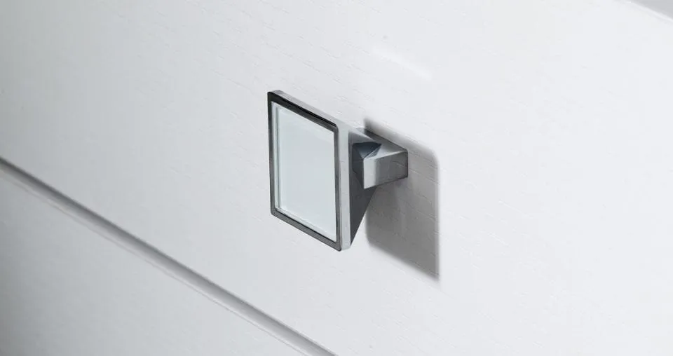 Close view of a square metal knob on a pale GEORGE cabinet front with a horizontal joint.