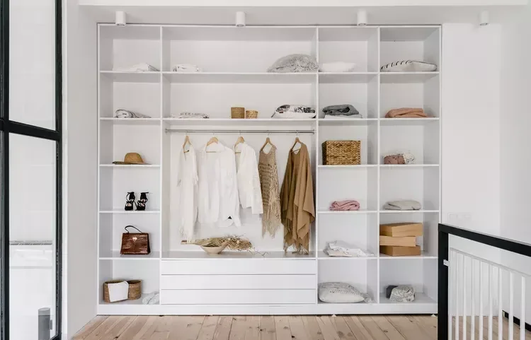 Open white wardrobe with hanging rails, drawers and shelves