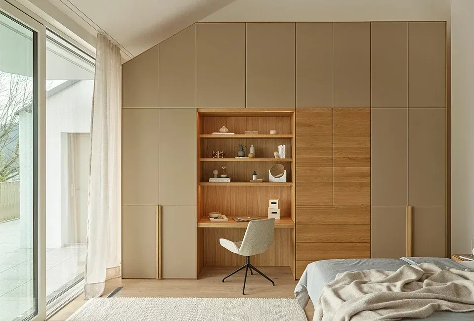 GEORGE illustrative attic wardrobe design with hinged cabinet fronts shaped around a descending ceiling and a recessed desk at the centre.